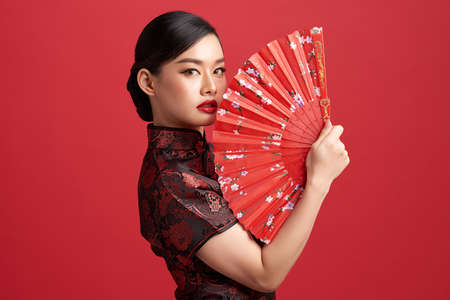 Asian chinese woman in traditional dress on red background. Chinese new year festivalの写真素材