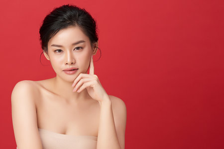 Beautiful young asian woman with clean fresh skin on red background, Face care, Facial treatment, Cosmetology, beauty and spa, Asian women portrait.の写真素材