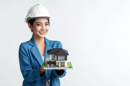 Beauty young asian woman engineer holding showing house model on white background, construction concept, Engineer, Industry.の写真素材