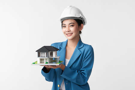 beautiful young asian woman engineer holding showing house model on white background, construction concept, Engineer, Industry.の写真素材