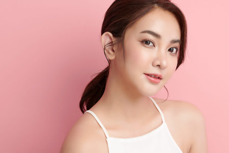 Beautiful young asian woman with clean fresh skin on pink background, Face care, Facial treatment,...