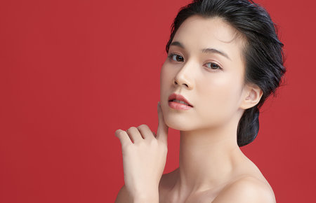 Beautiful young asian woman with clean fresh skin on red background, Face care, Facial treatment, Cosmetology, beauty and spa, Asian women portrait.の写真素材