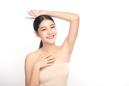 Beautiful Young Asian woman Raises her hands to Showcase clean and hygienic underarms Against a white background, Smooth armpit cleanliness and protection conceptの写真素材