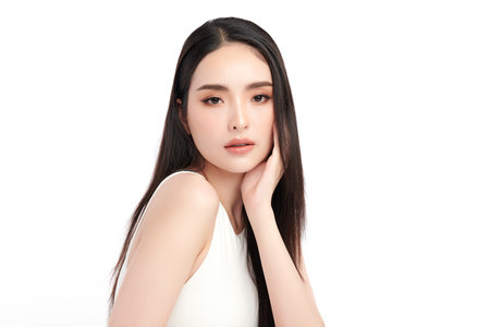 A beautiful young Asian woman with clean, fresh skin against a white background. Skincare, facial treatment, cosmetology, beauty, and spa. An elegant portrait of an Asian woman.の写真素材