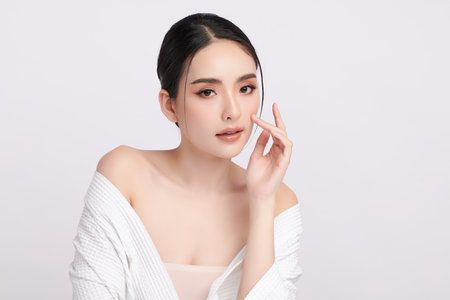 A beautiful young Asian woman with clean, fresh skin against a white background. Skincare, facial treatment, cosmetology, beauty, and spa. An elegant portrait of an Asian woman.の写真素材