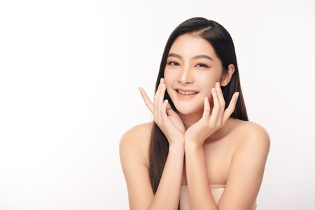 A beautiful young Asian woman with clean, fresh skin against a white background. Skincare, facial treatment, cosmetology, beauty, and spa. An elegant portrait of an Asian woman.の写真素材