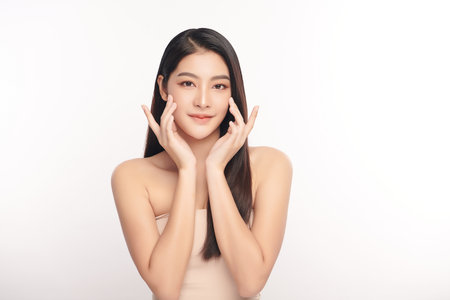 A beautiful young Asian woman with clean, fresh skin against a white background. Skincare, facial treatment, cosmetology, beauty, and spa. An elegant portrait of an Asian woman.の写真素材