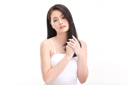 A beautiful young Asian woman with clean, fresh skin against a white background. Skincare, facial treatment, cosmetology, beauty, and spa. An elegant portrait of an Asian woman.の写真素材