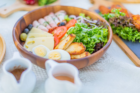 Salad with ham, eggs, cheese and vegetables in wooden bowlの写真素材