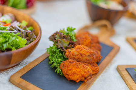 Fried chicken nuggets with fresh salad on wooden board, selective focusの写真素材