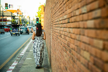 Asian woman standing in front of a brick wall in Bangkok, Thailandの写真素材