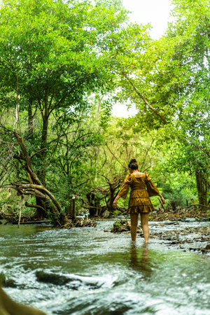 Young woman walking in the middle of a stream in the jungle.の写真素材