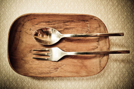 Stainless fork and spoon on wood plateの写真素材