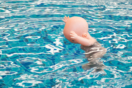 Baby doll floating in a swimming pool, The dangers of children drowning.の写真素材