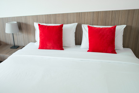 Red and white pillows on a bedの写真素材