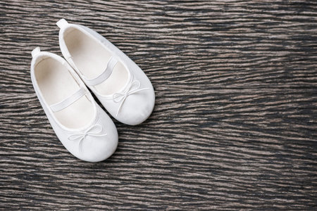 White baby shoe on wooden background , top viewの写真素材