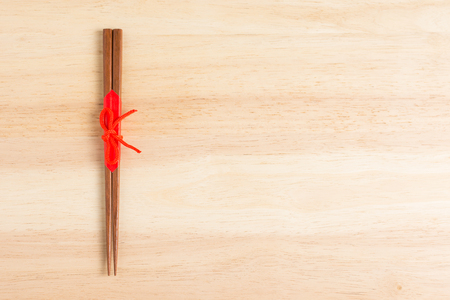Japanese wooden chopsticks wrapped in red paper and red rope on wooden table.の写真素材