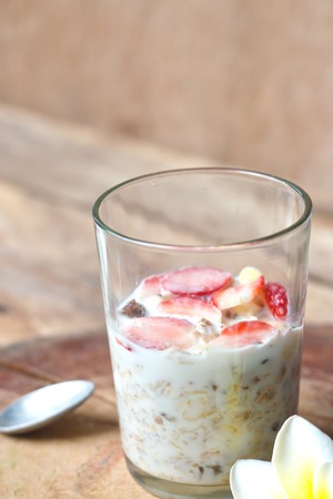 Crunchy musli (whole grain oats) served with fresh strawberries and low fat yogurt in a glass bowl - healthy breakfast.の写真素材