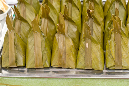 Thai traditional sticky rice dessert in banana leaf packaging.の写真素材