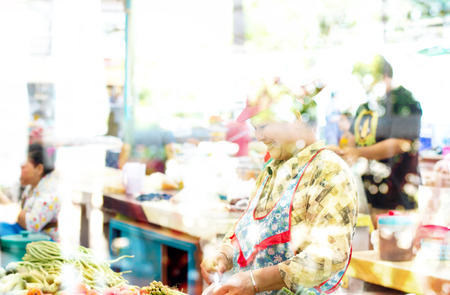 Nongkhai, Thailand - May 09, 2015: Creative double exposure  Unidentified smiling shop owner of vegetable shop packing her goods befor sell to customer with blured bokeh background.のeditorial素材
