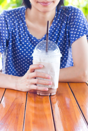 Asian women holding Iced coffee with milk on the table.の写真素材