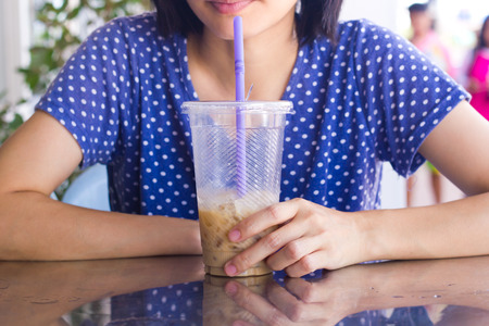 Asian women holding Iced coffee with milk on the table.の写真素材