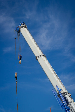 The construction crane for heavy lifting against a blue sky background.