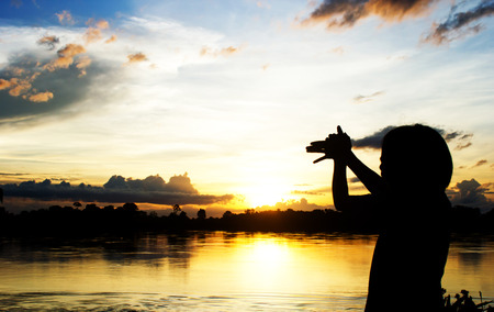Silhouettes Women make dog sign by her hand over beautiful sun set background.の写真素材