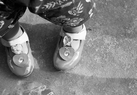 Closeup of cute Red shoes with a little girl standing on out door hard floor.Focused on red shoes.の写真素材