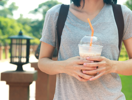 Asian women holding Iced coffee with milk in plastic glass.の写真素材