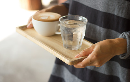 Waiter serving coffee on poor lighting.Focused at Right hand.の写真素材