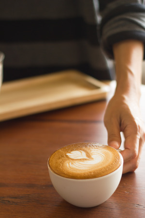 Waiter serving coffee on poor lighting.Focused at coffee cup.の写真素材