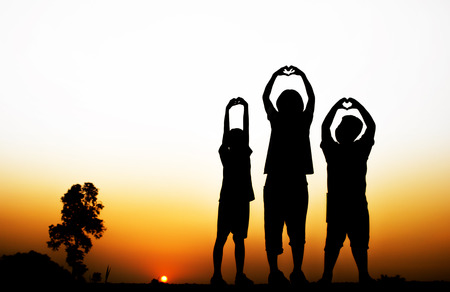 Blurred Silhouette of children make heart with beautiful sunset background.の写真素材