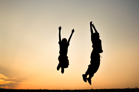 Defocused Silhouette of a boy is jumping over beautiful sunset background.の写真素材