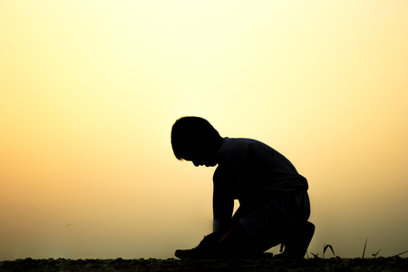 Running and jogging exercising concept. Silhouette of a boy  tying laces before training .の写真素材