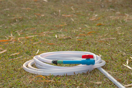 plastic hose with plastic pipe valve on grass feild.の写真素材