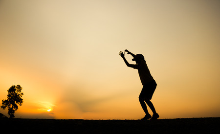 Silhouette of a women is jumping over beautiful sunset background.の写真素材
