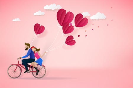Happy couple is riding a bicycle together  and holding red balloons on pink  background.  Illustration of Love and Valentine Day. Paper cut style.の写真素材