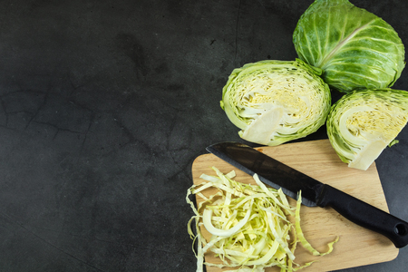 Finely chopped cabbage on a chopping board And cauliflower on black ground.の写真素材