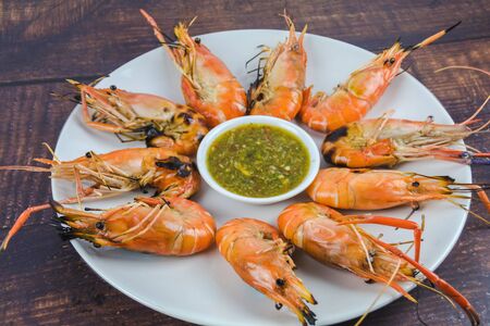Shrimp in a white dish with seafood sauce on a wooden floor.の写真素材