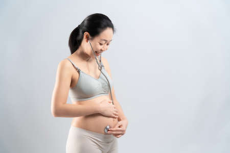 Asian pregnant woman use the stethoscope listening infant her selfの写真素材