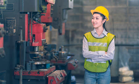 The Engineer yellow safety helmet walking and smile check the machine in the industrial factoryの写真素材