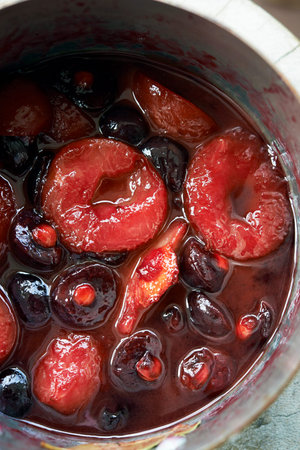 poached prunes and cherries in pot,close up