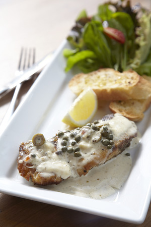 Fried fish in white sauce serve with bread and saladの写真素材