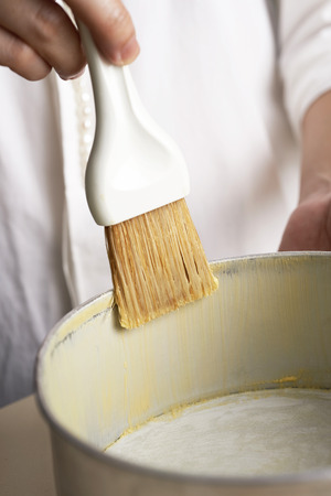 Hand brushing butter inside cake trayの写真素材