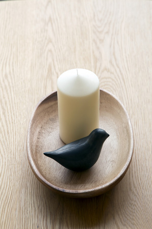 Candle and ceramic bird in bowl on wooden backgroundの写真素材