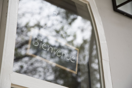 Bienvenue sign in glass window with reflection of tree outsideの写真素材