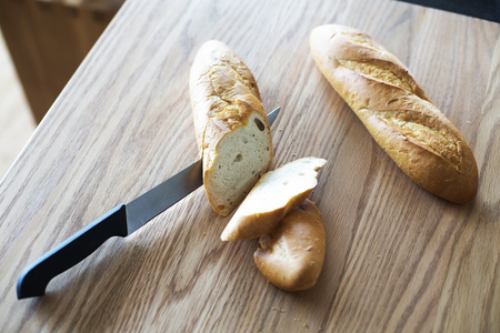 Knife cutting baguette on the wooden boardの写真素材