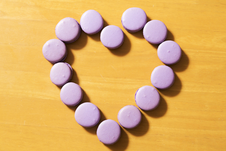 Purple color Macaroons row in heart shape on tableの写真素材