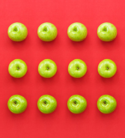 Green fresh apples on red paper background
